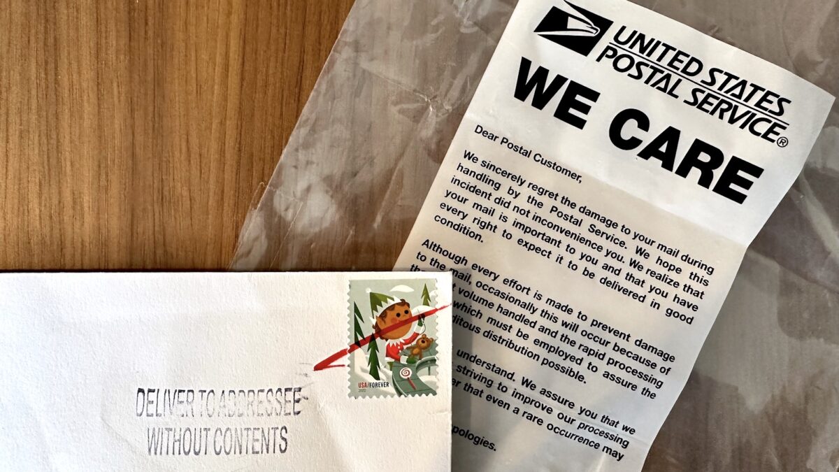 USPS "we care" bag next to a crumpled envelope, zoomed in