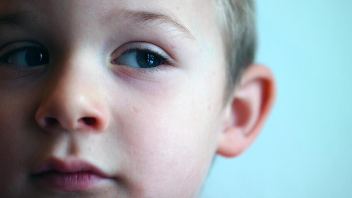 close up of little boy's face on blue background