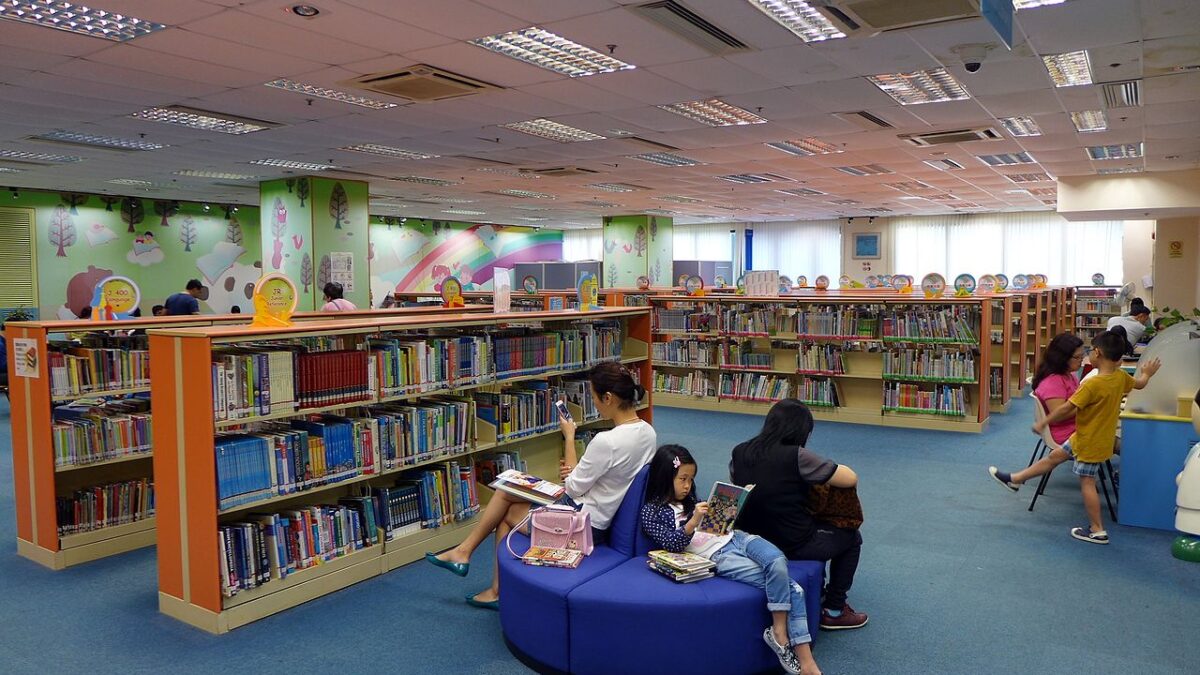 children sit reading on couches in children's section of public library