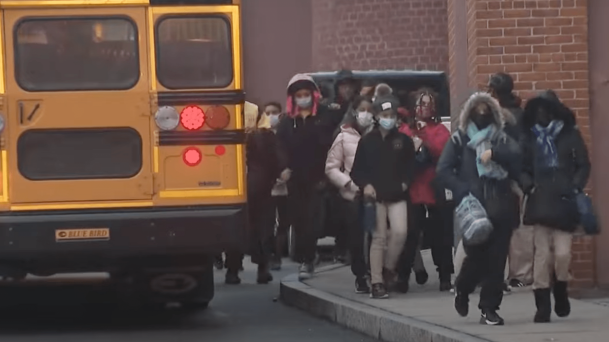 schoolchildren in masks getting off the bus