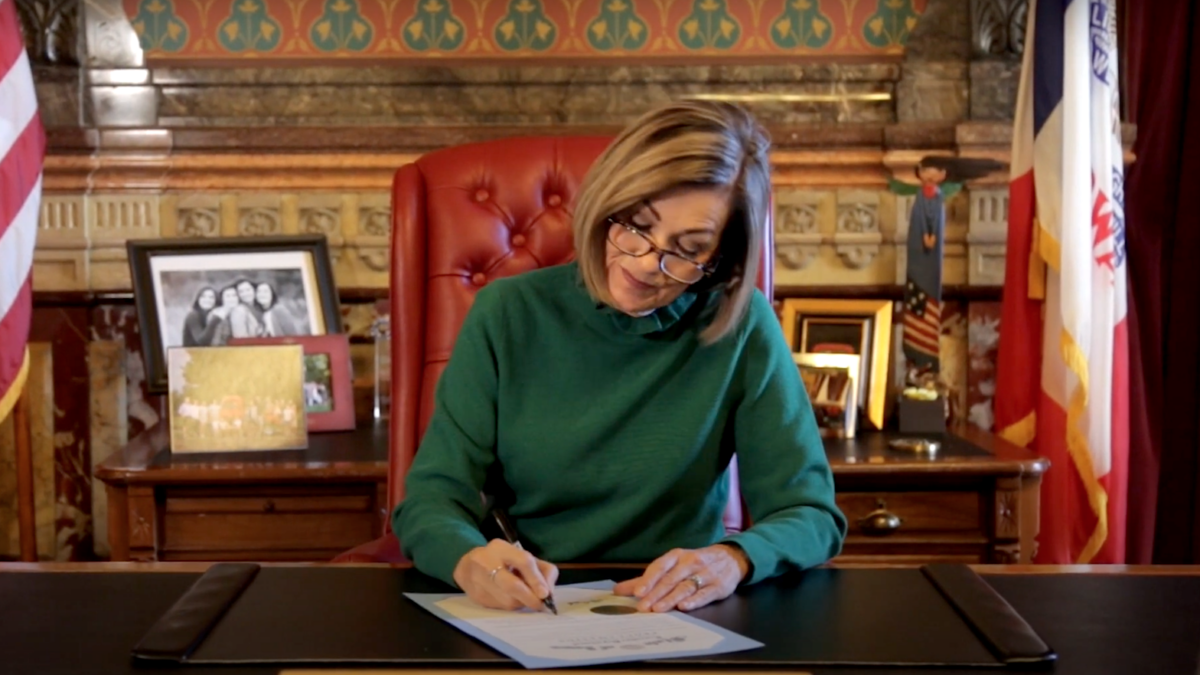 Iowa Gov. Kim Reynolds signing a document
