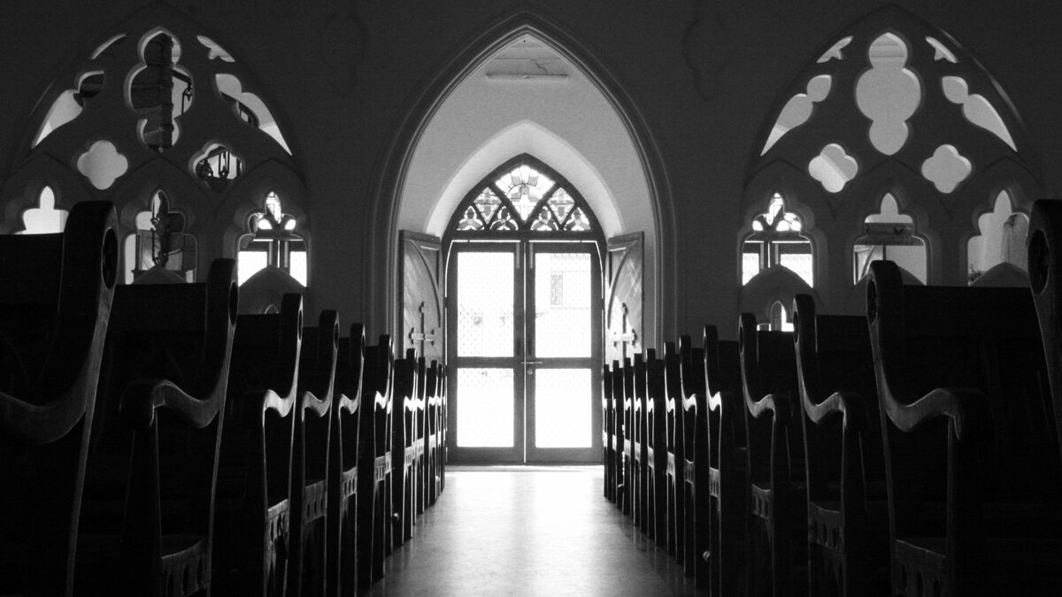 black and white picture of church pews, windows and door