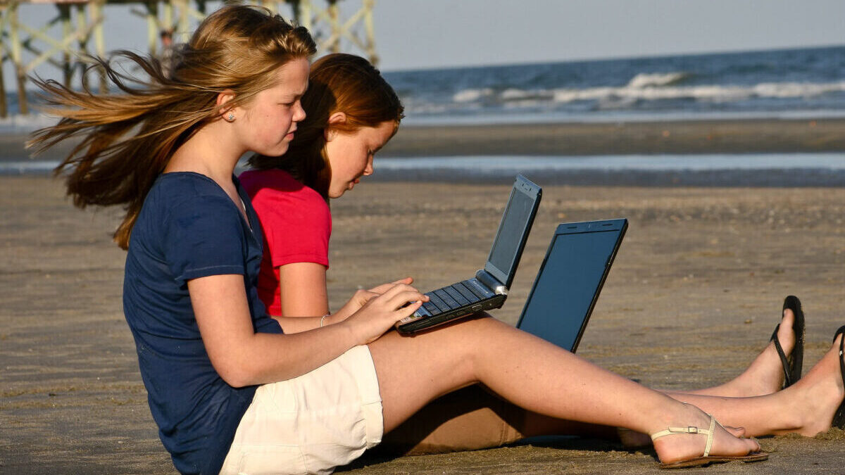 girls with laptops on the beach