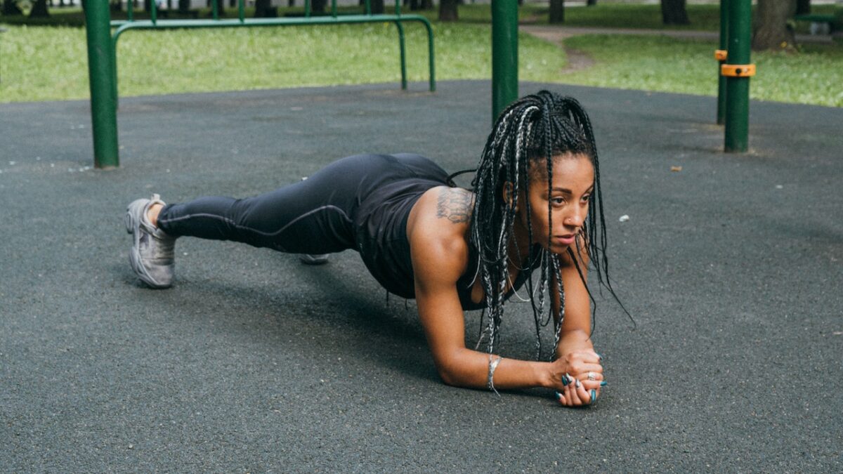 fit black woman exercising by doing a plank