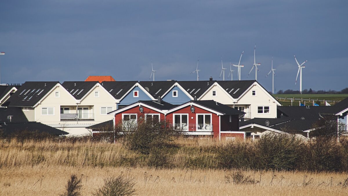 houses with wind turbines in the distance.