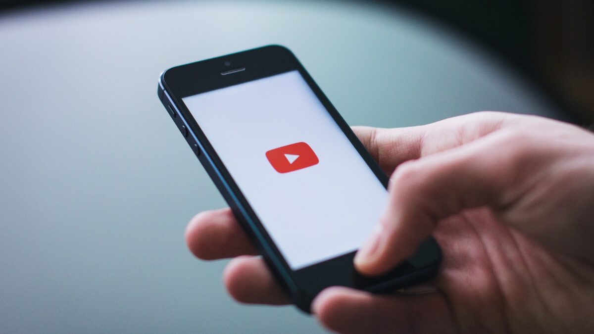 hand holding phone with YouTube icon on screen