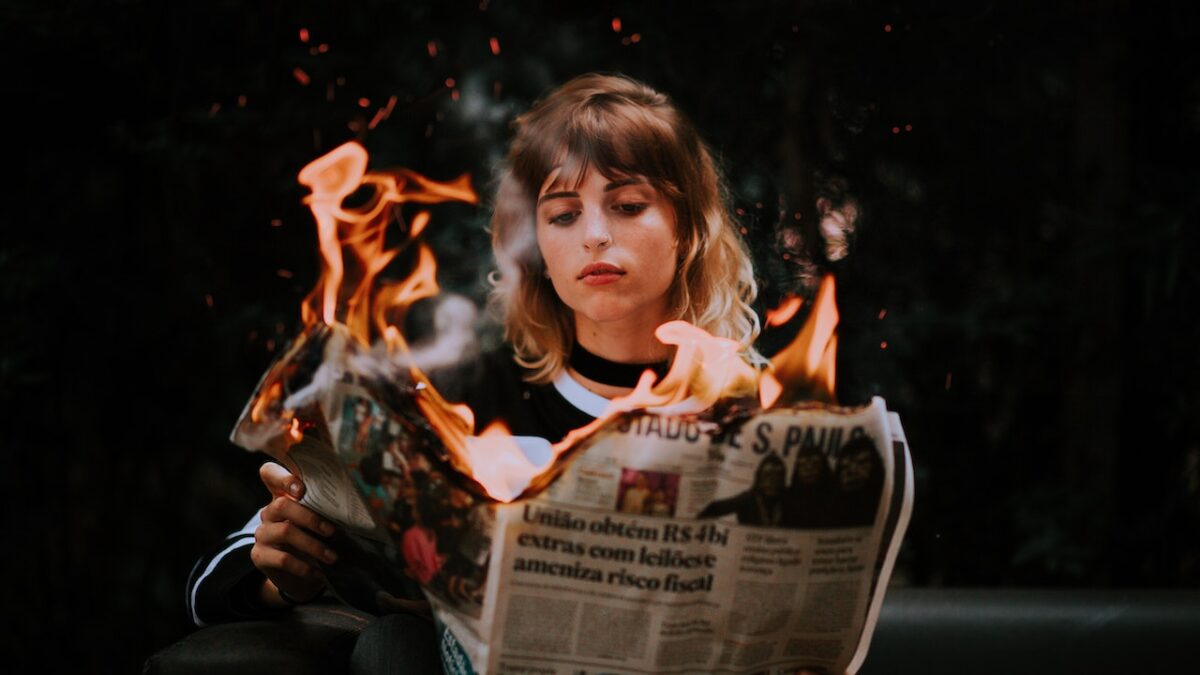 woman holding a newspaper that's on fire