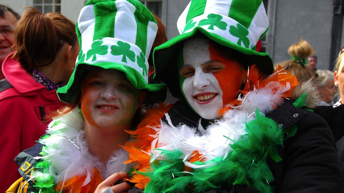 two parade attendees with face paint and green and white shamrock hats
