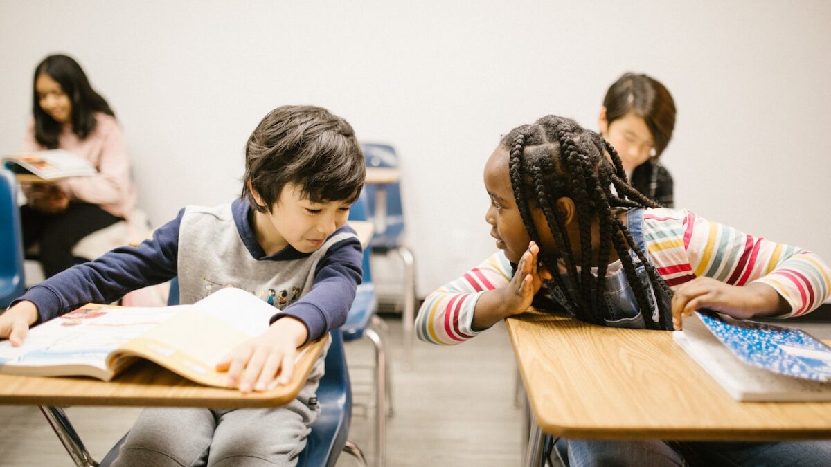 Two children of different races talk to each other in a classroom