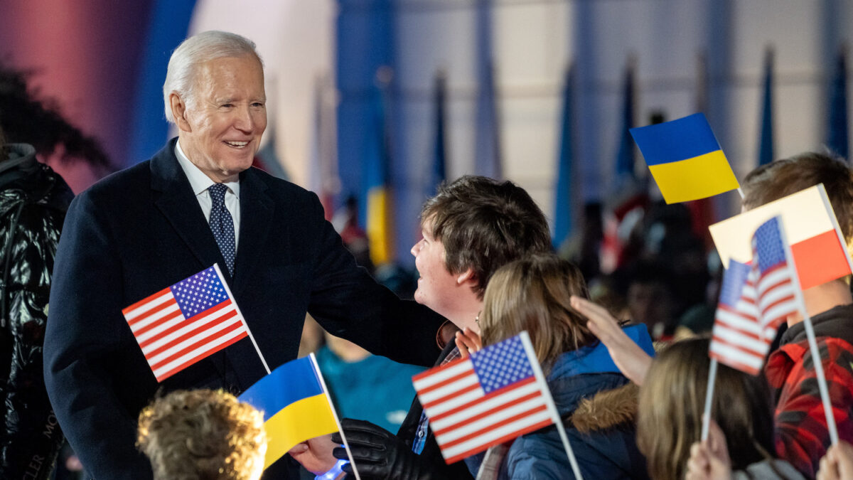 Joe Biden stands with group of children waving flags