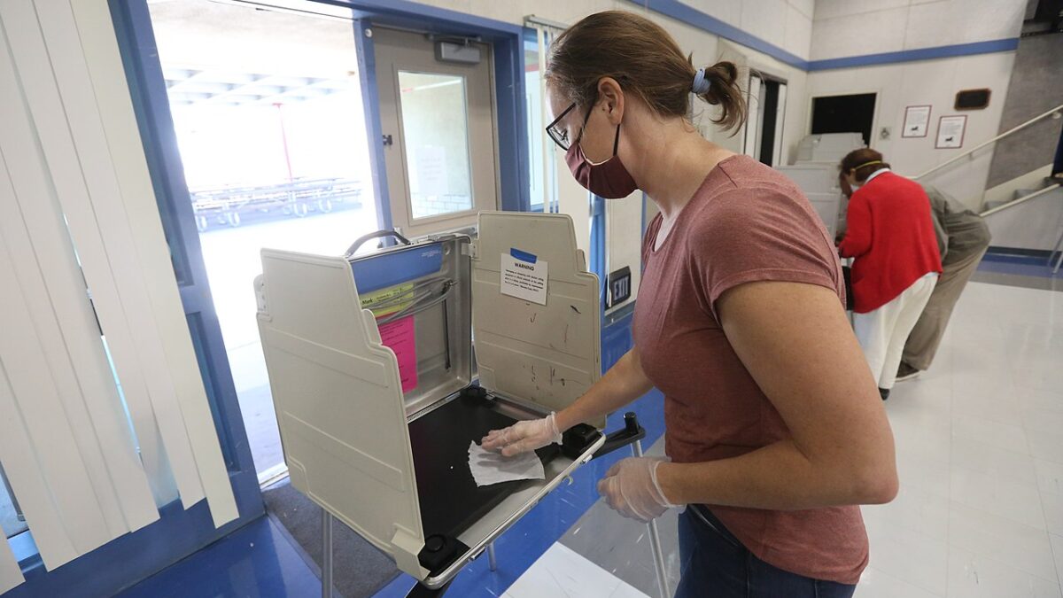 A California poll worker sanitizes a voting booth following its use at a Voter Assistance Center in Davis, CA during the 2020 General Election.