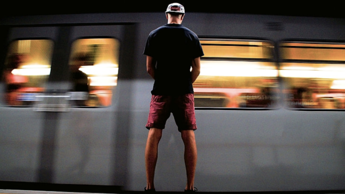 man standing in front of moving subway train
