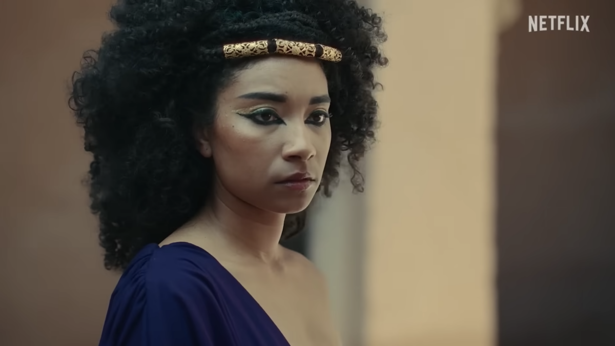 black Cleopatra wearing purple dress and gold headband