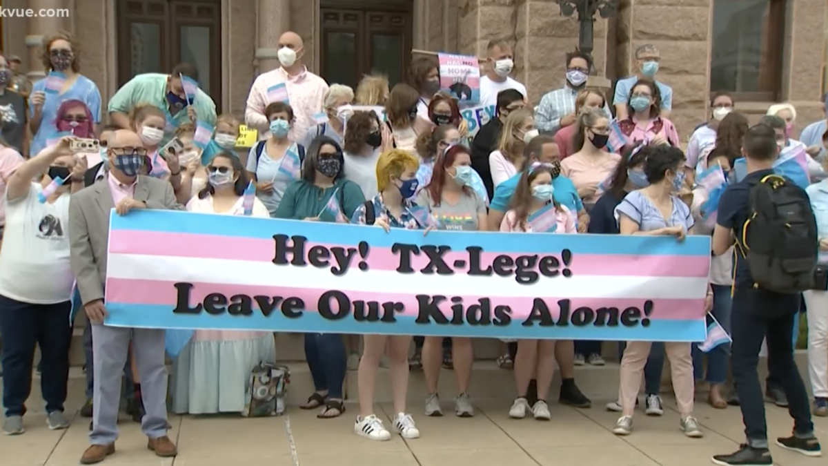 trans kids protesting on capitol steps with pink and blue banner