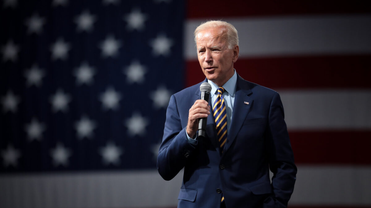 Joe Biden with a microphone and American flag in the background