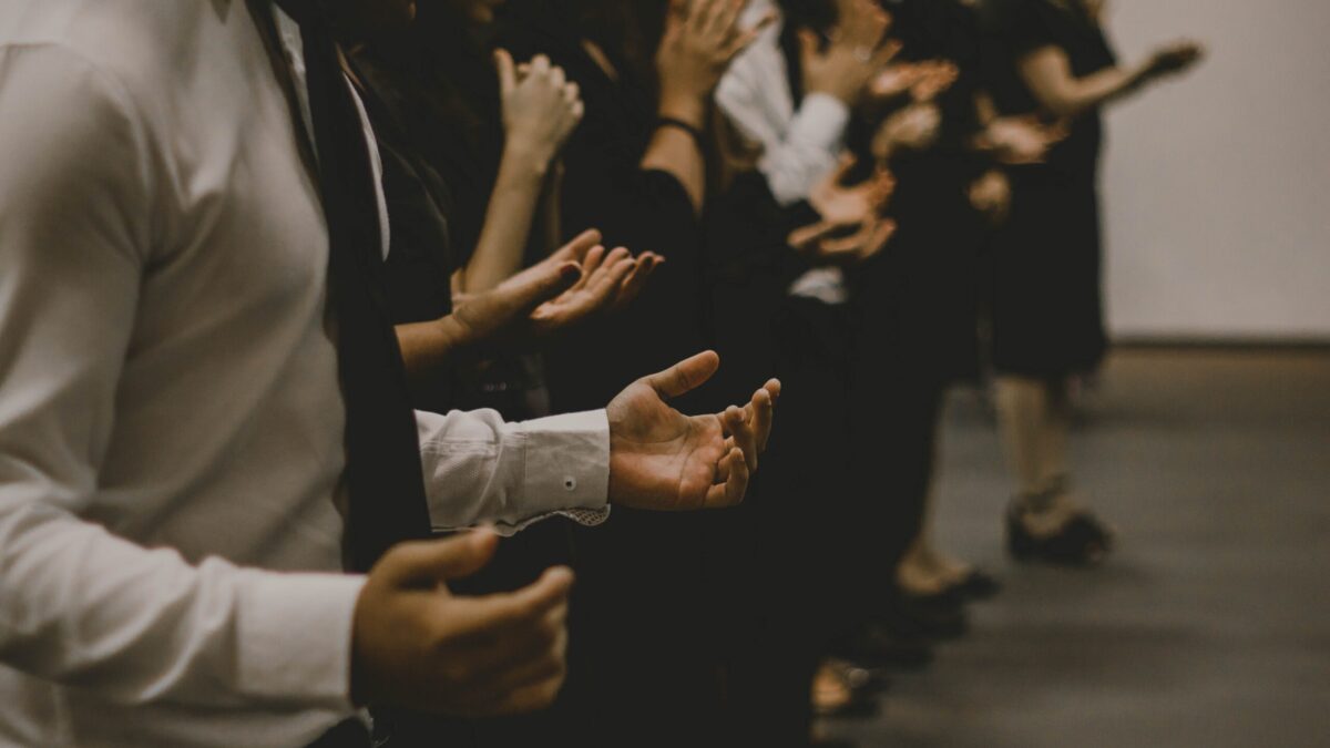 Line of people with hands extended in prayer.
