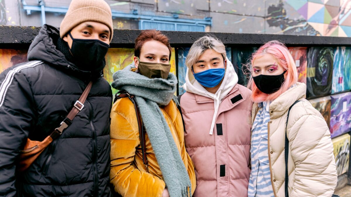 Four people standing next to each other wearing masks.
