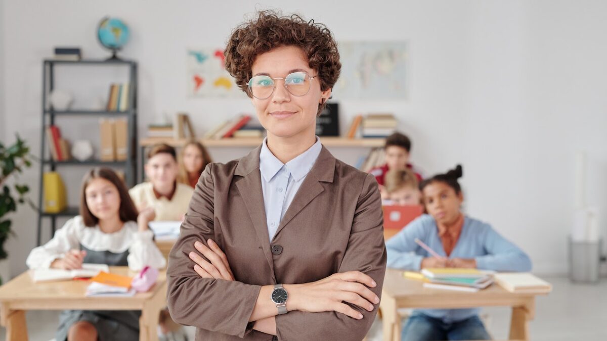 A woman teacher stands smugly in front of children