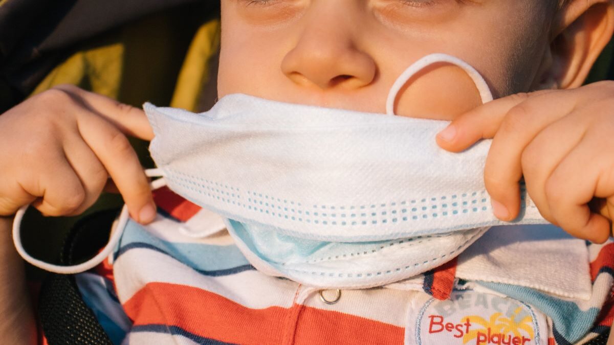 A child putting a medical mask over his mouth