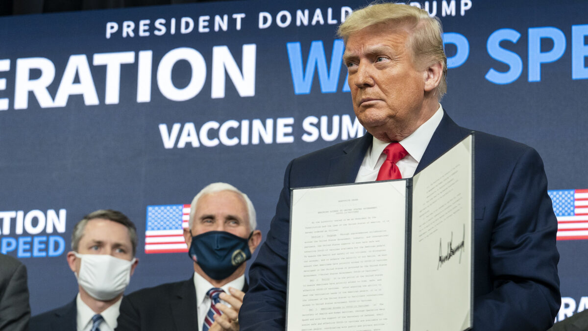 Trump, joined by Vice President Mike Pence and senior White House staff, displays his signature after signing an Executive Order ensuring that the American people have priority access to COVID-19 vaccines