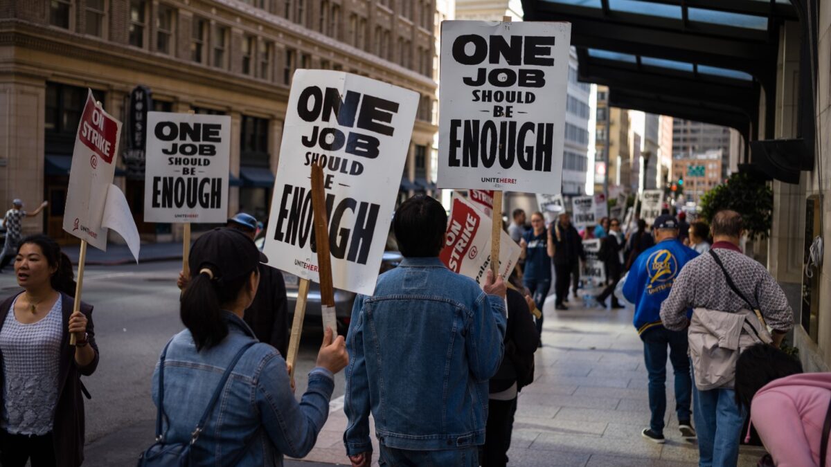 union protesters holding signs that say "one job should be enough"