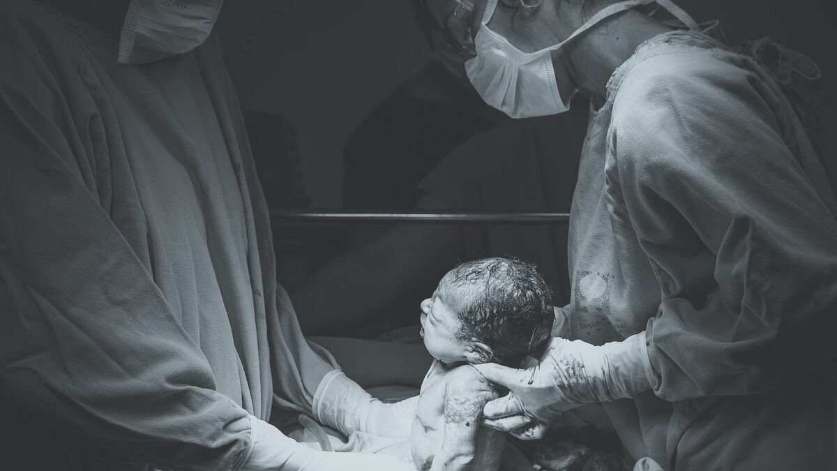 doctors holding newborn baby in operating room
