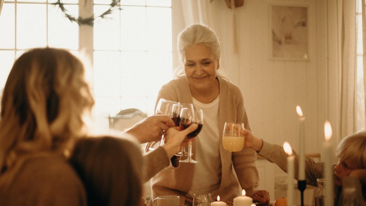 Grandmother clinking wine with other women around table