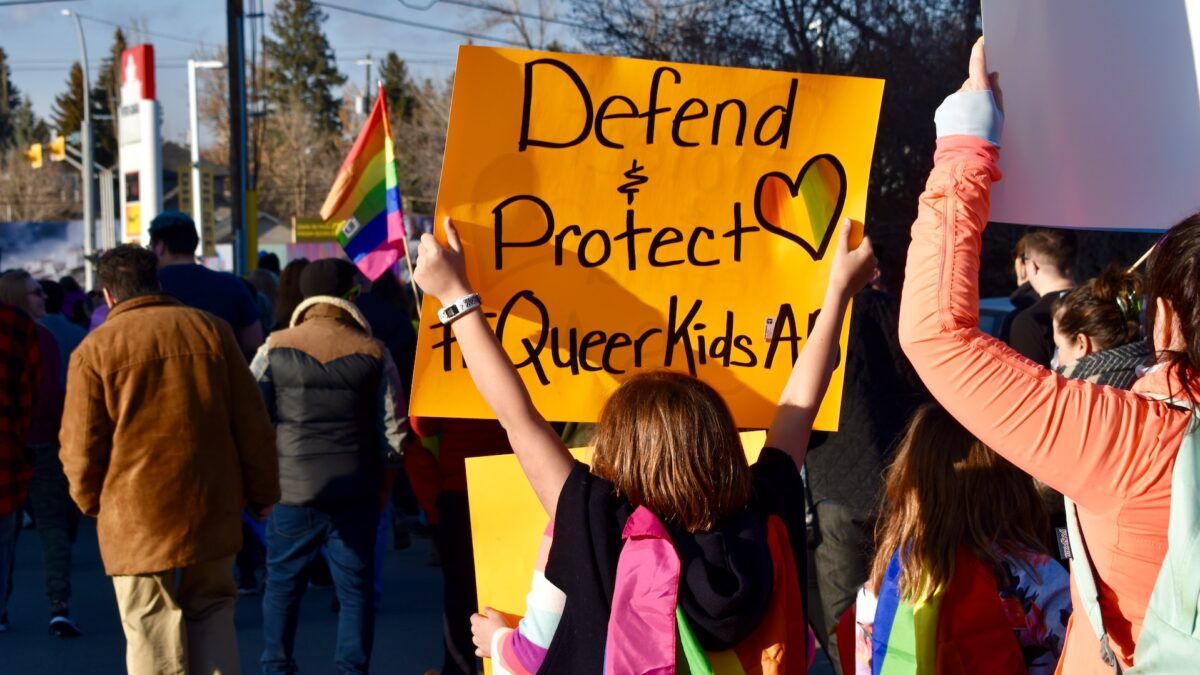 transgender kid holding queer sign at protest