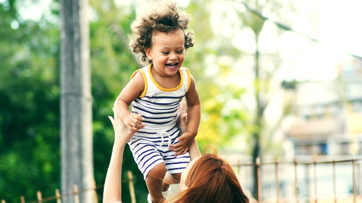 woman throwing laughing toddler into the air