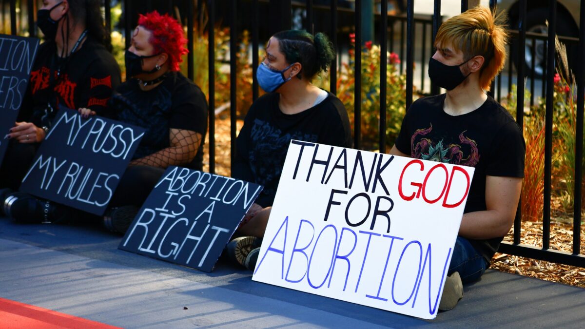 protesters sit on the ground holding pro-abortion signs