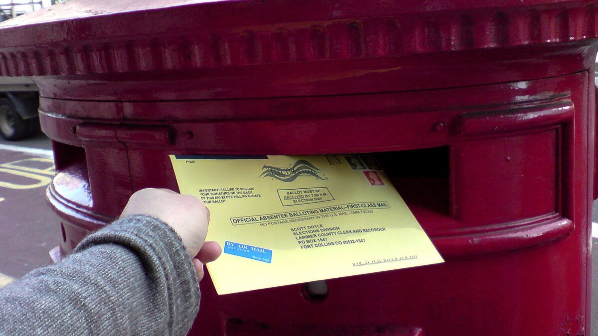 Unidentified person dropping a ballot in a collection box.