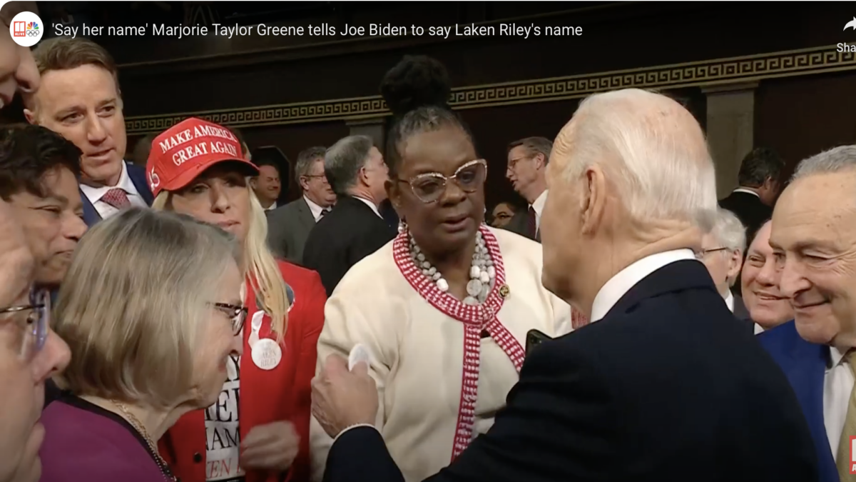 U.S. Rep. Marjorie Taylor Greene hands President Joe Biden a pin that states "Say Her Name" Laken Riley before the State of the Union Address.