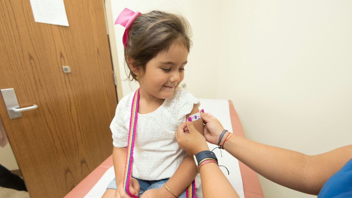 little girl getting a band-aid from a nurse