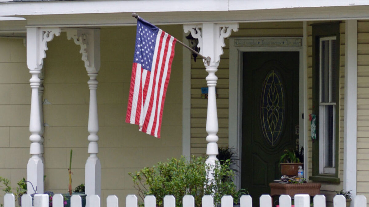American flag hanging on a house front porch