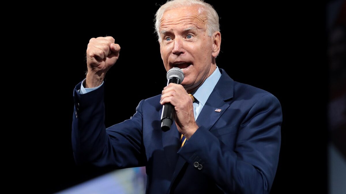 Joe Biden speaking into a microphone with fist extended.