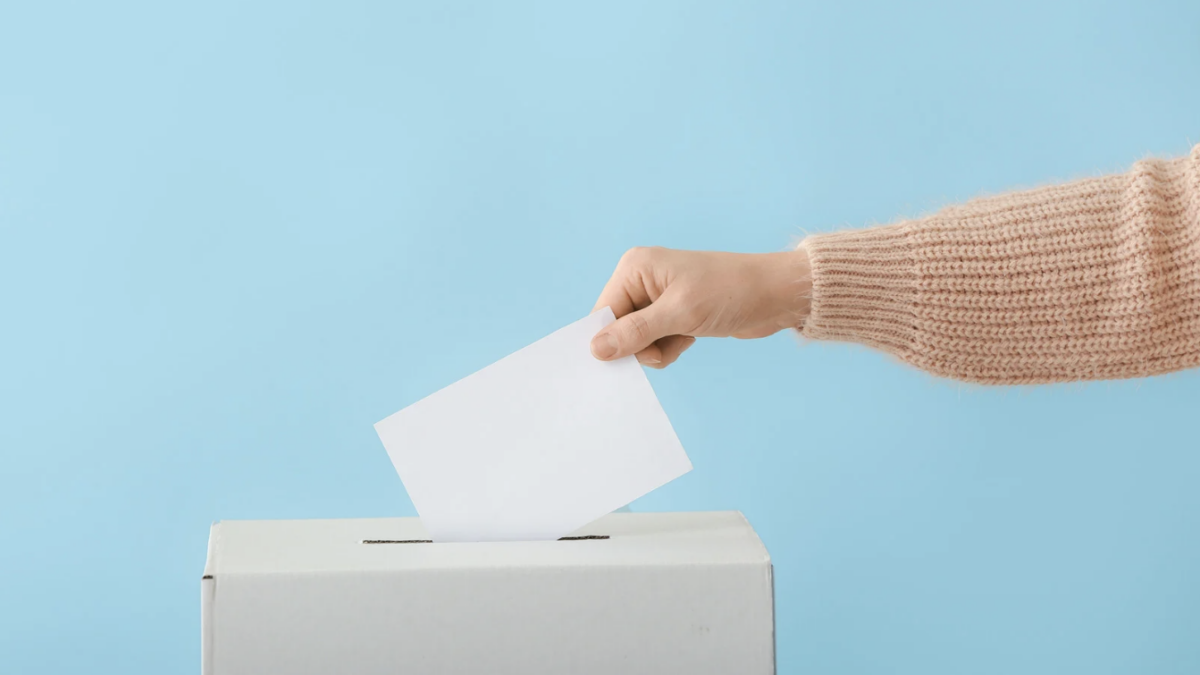 person placing ballot into a box