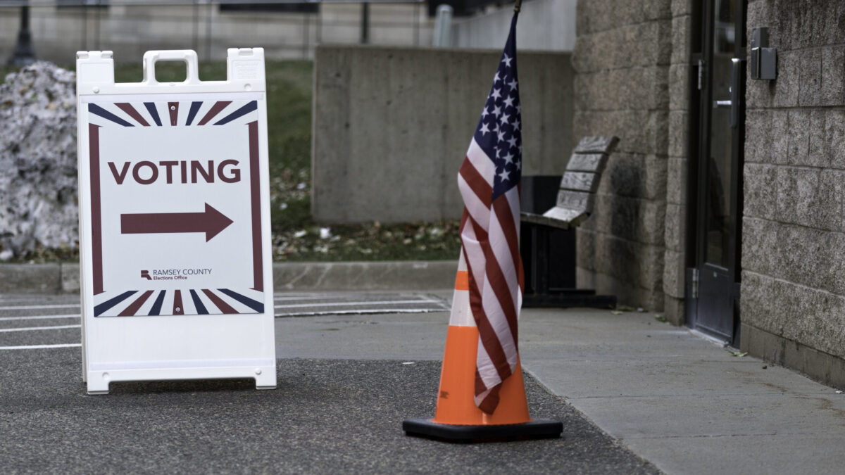 Voting sign near an American flag.
