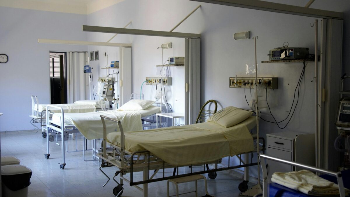 Three empty hospital beds along a wall.