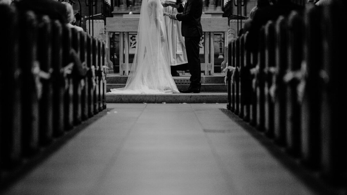 Grayscale bride and groom marriage ceremony at church altar