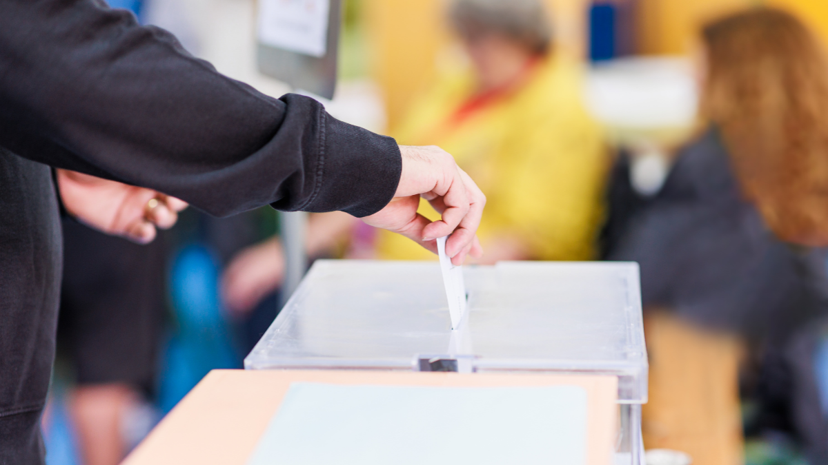 person casting a ballot in a box