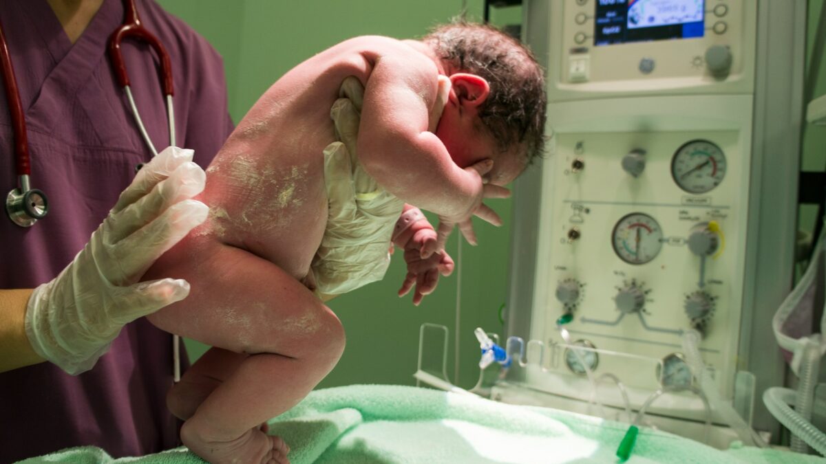 newborn baby held by nurse at hospital