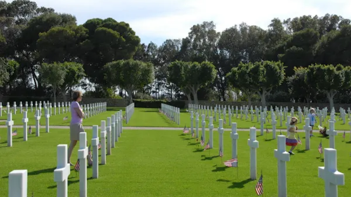 Woman and children are walking through military cemetery.