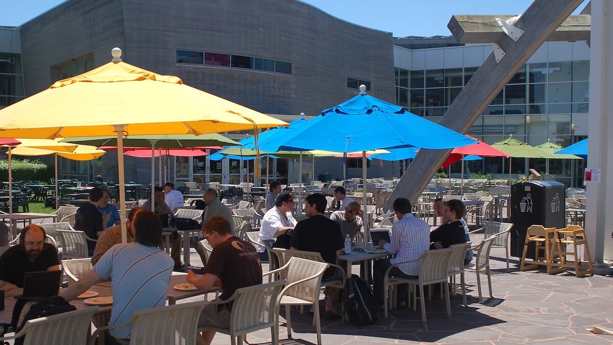 people eating outdoors at a restaurant at umbrella tables