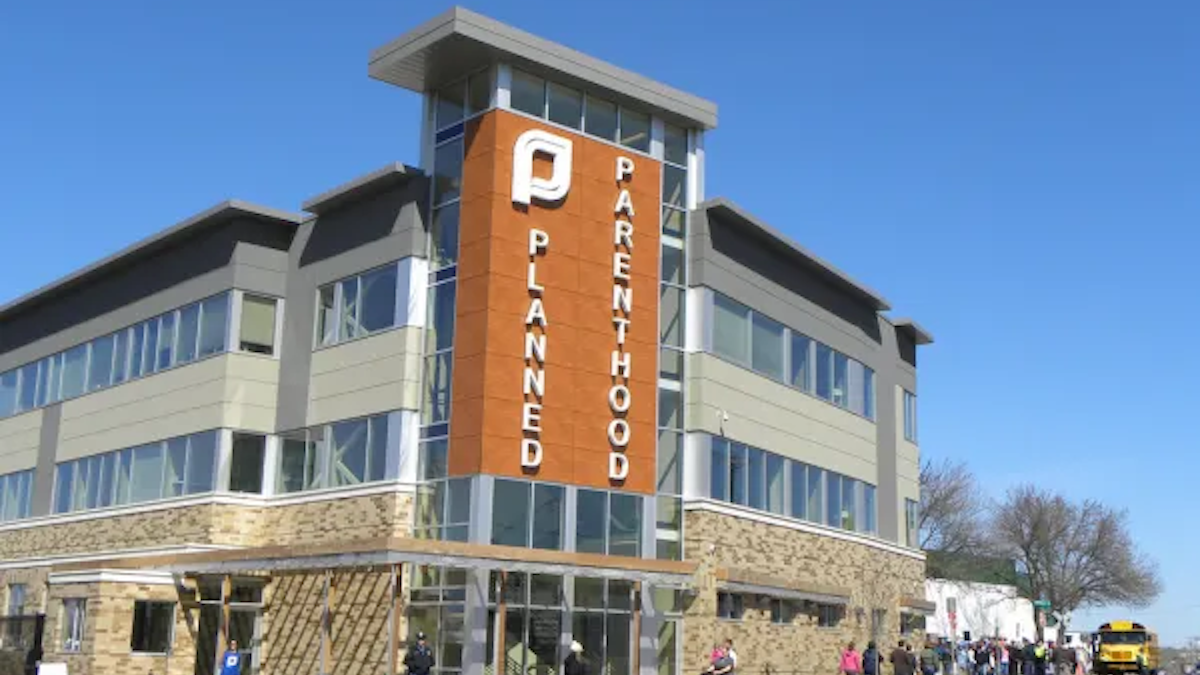 A Planned Parenthood building where the sign is visible and people are walking around outside.