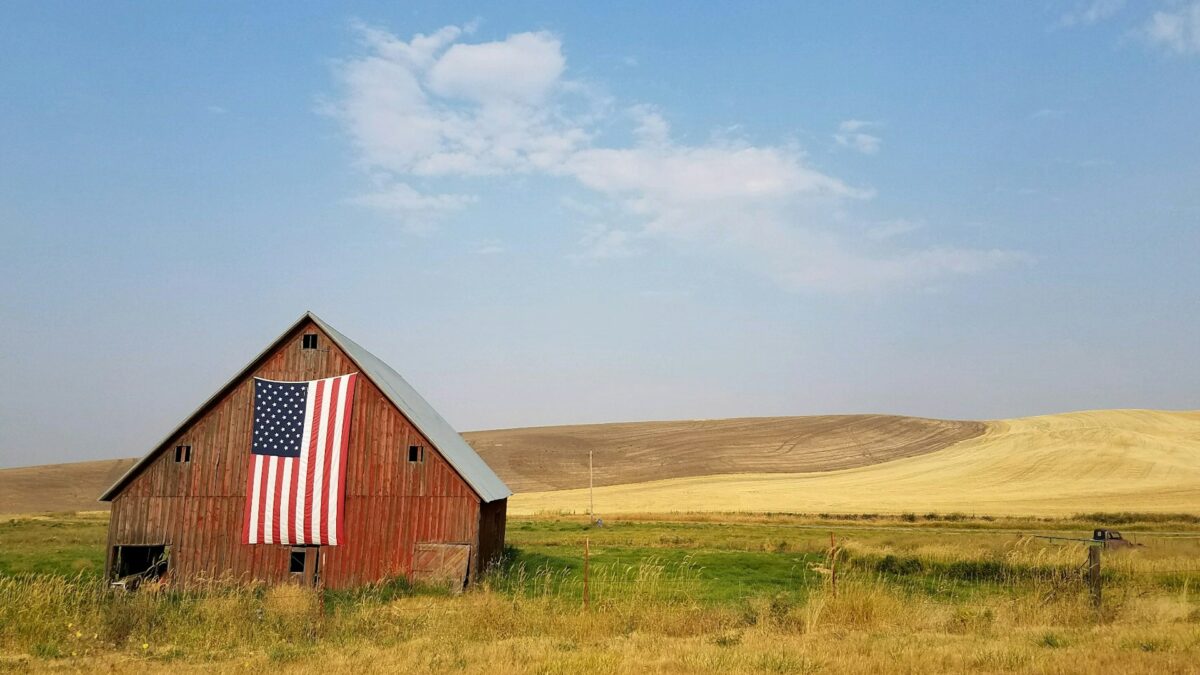 american flag on barn in a field