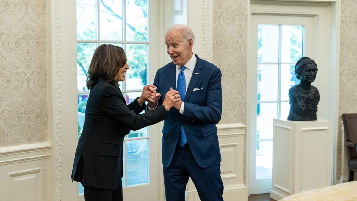 Biden and Harris talk while holding hands.