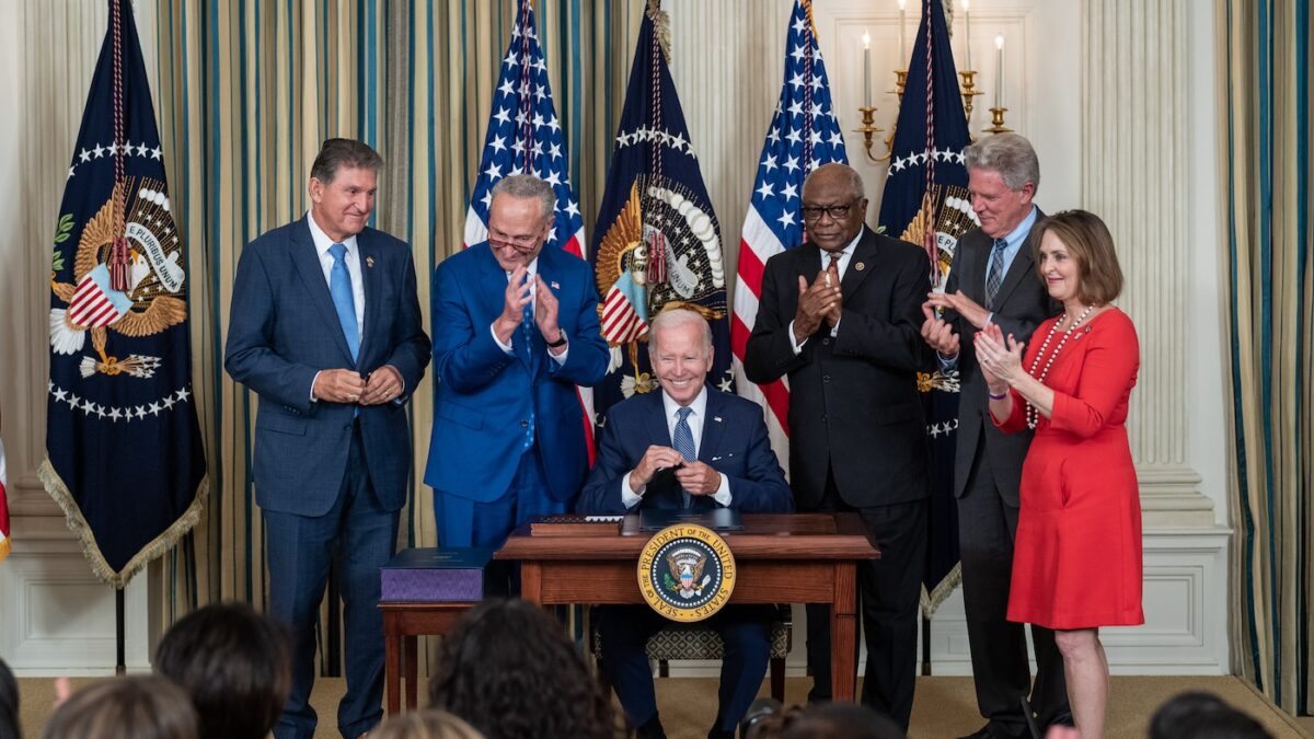 Biden surrounded by members of Congress signs the inflation reduction act