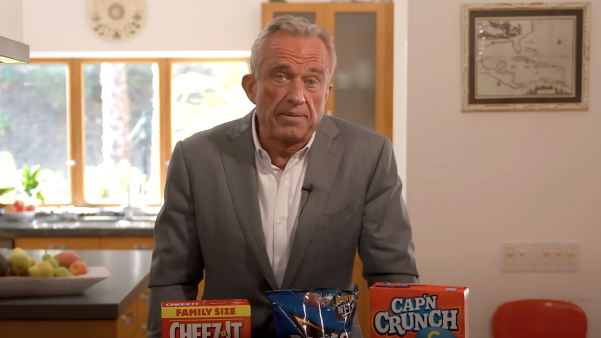 RFK Jr. stands at kitchen counter behind junk food