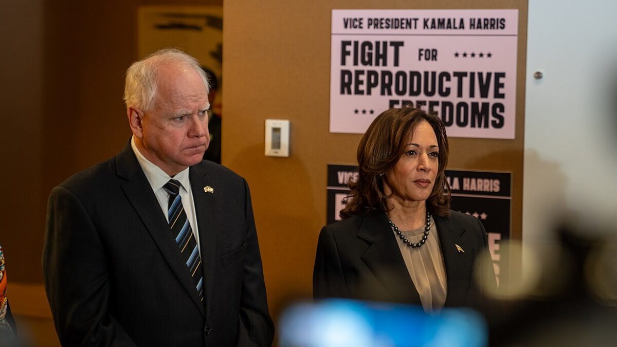 Tim Walz and Kamala Harris stand in front of 