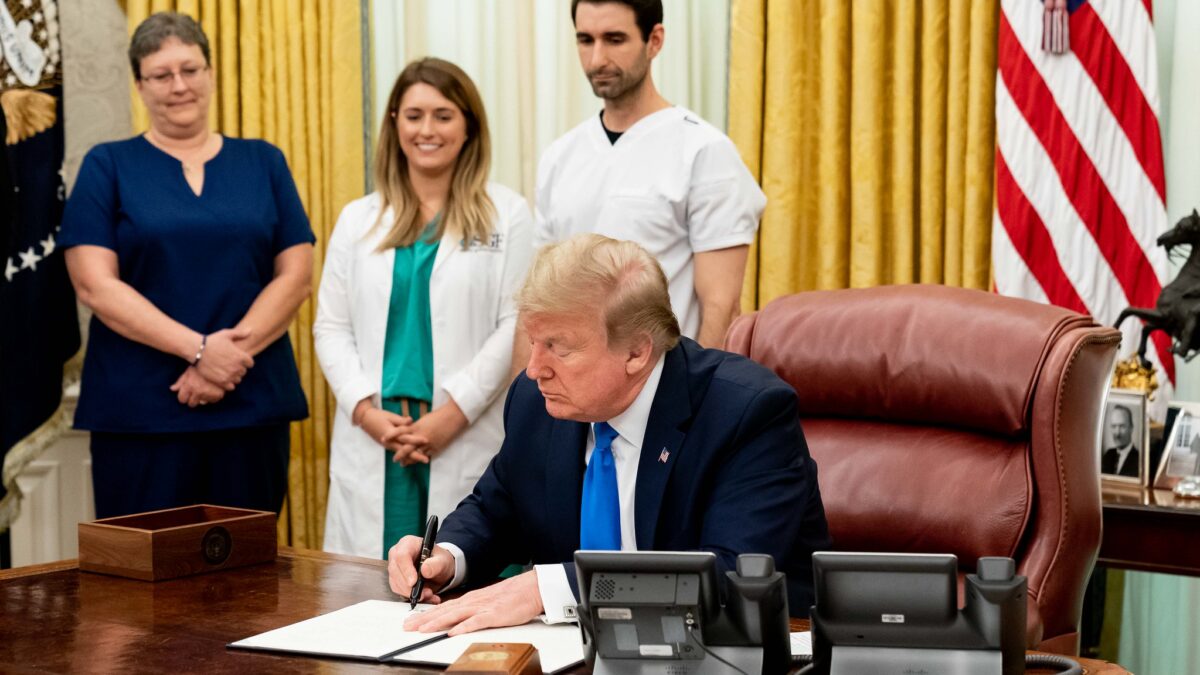 Trump signs bill with nurses in background